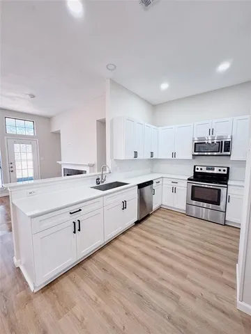 a large white kitchen with stainless steel appliances granite countertop a stove and a sink