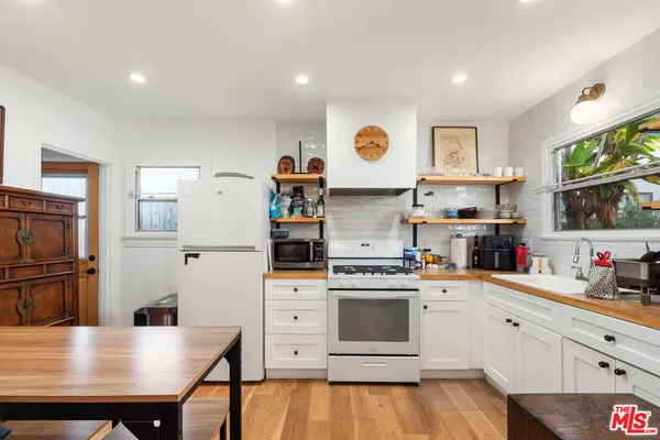 a kitchen with stainless steel appliances a stove a sink dishwasher and a refrigerator with wooden floor