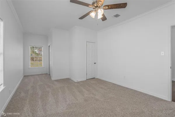 an empty room with windows and fan
