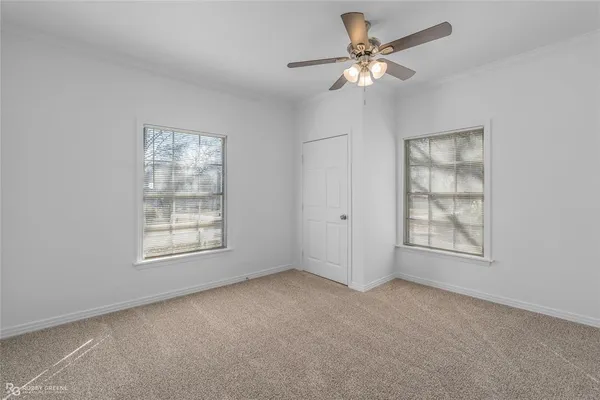 an empty room with chandelier fan and windows