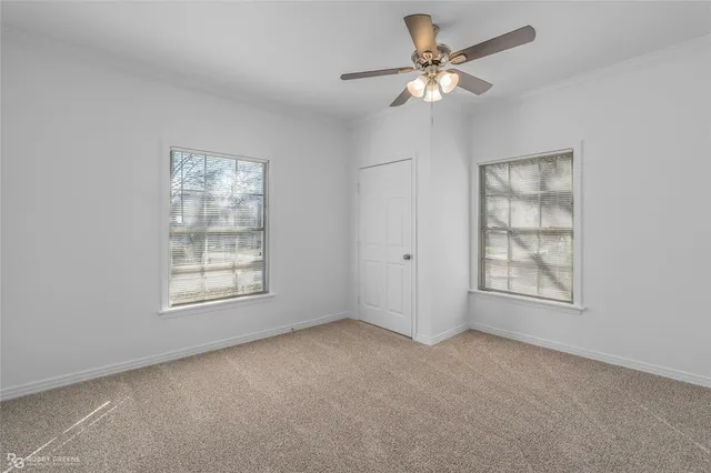 an empty room with chandelier fan and windows