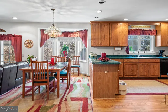 a kitchen with stainless steel appliances granite countertop a refrigerator a sink dishwasher a dining table and chairs with wooden floor