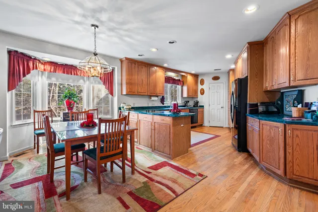 a kitchen with stainless steel appliances kitchen island granite countertop a refrigerator a stove top oven a sink dishwasher and wooden cabinets with wooden floor