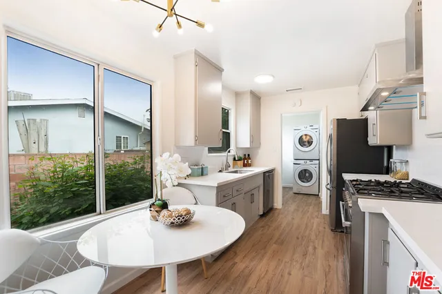 a kitchen with stainless steel appliances granite countertop a refrigerator a sink dishwasher a stove and white countertops with wooden floor