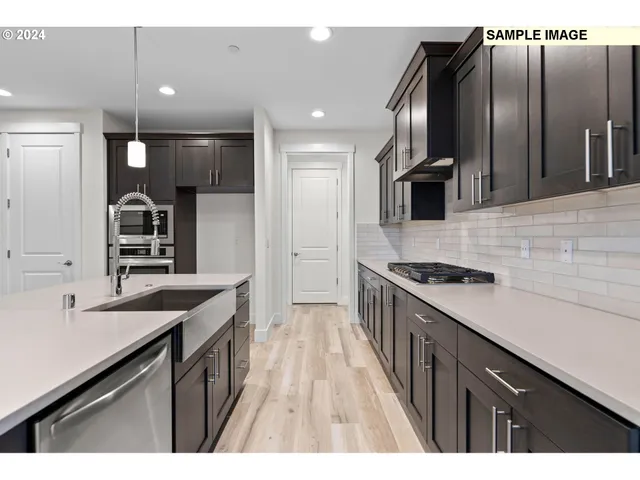 a kitchen with stainless steel appliances granite countertop a sink a stove and a wooden floors