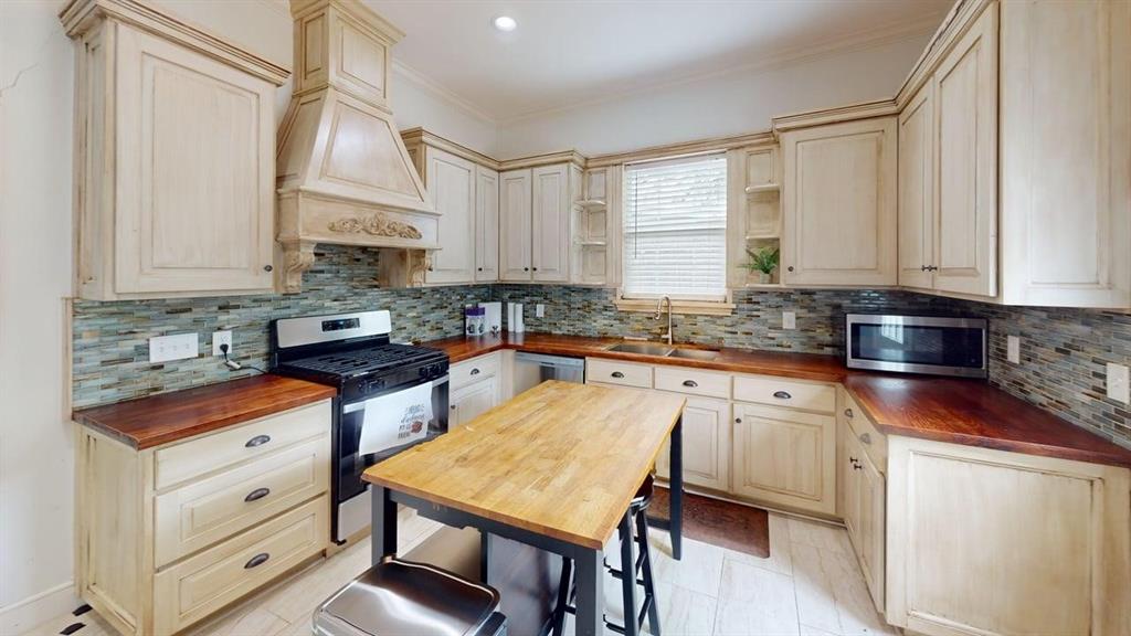 4523 Sycamore Street Dallas, TX 75204 - Photo 2 of 16 Kitchen featuring light-toned cabinetry, wood-finish countertops, and a full tile backsplash
