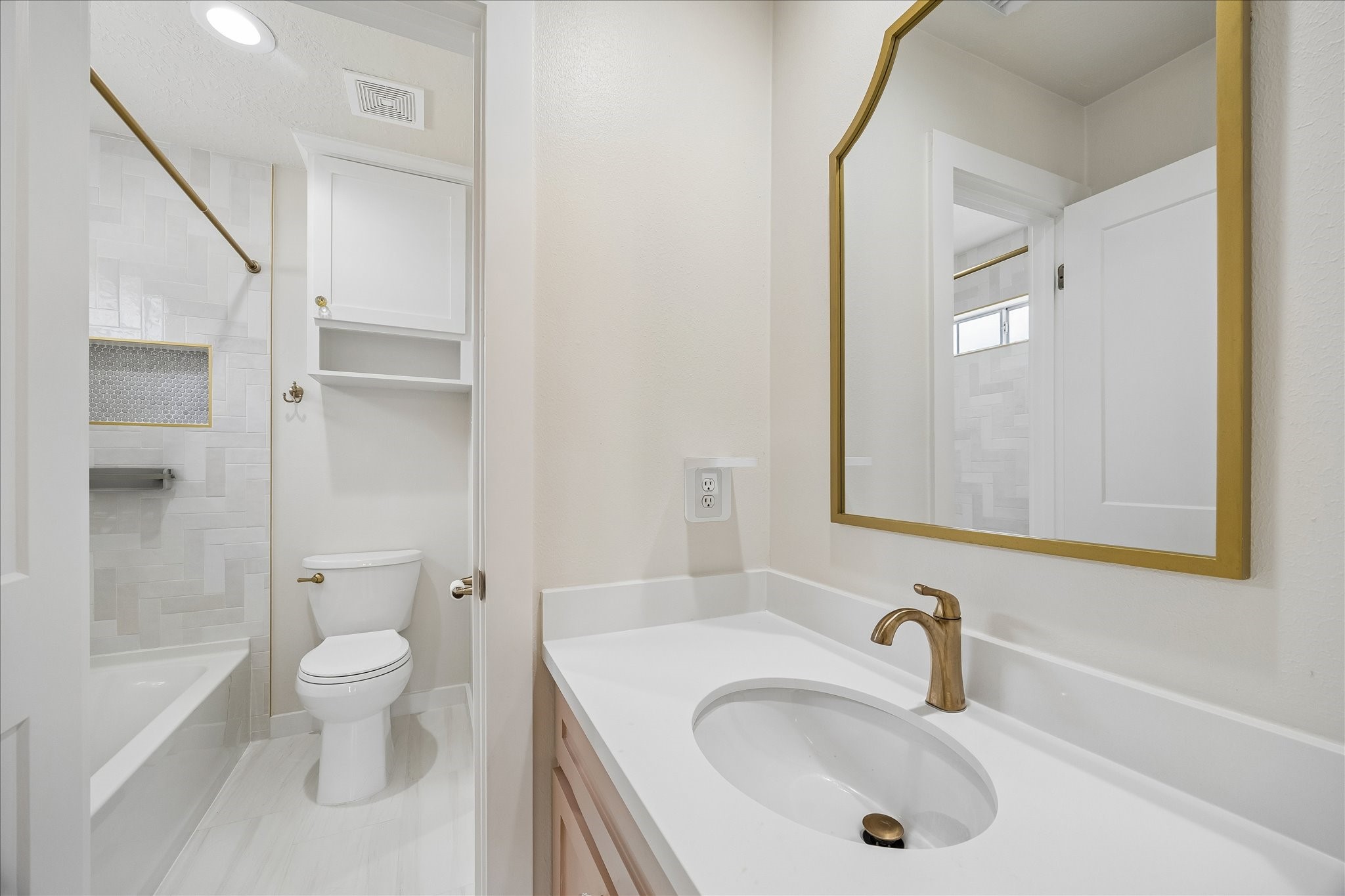 7915 Huddersfield Court Spring, TX 77379 - Photo 32 of 37 Updated Jack & Jill guest bath with modern tilework, tub/shower combination, brass accents, framed mirror, and clean neutral finishes.