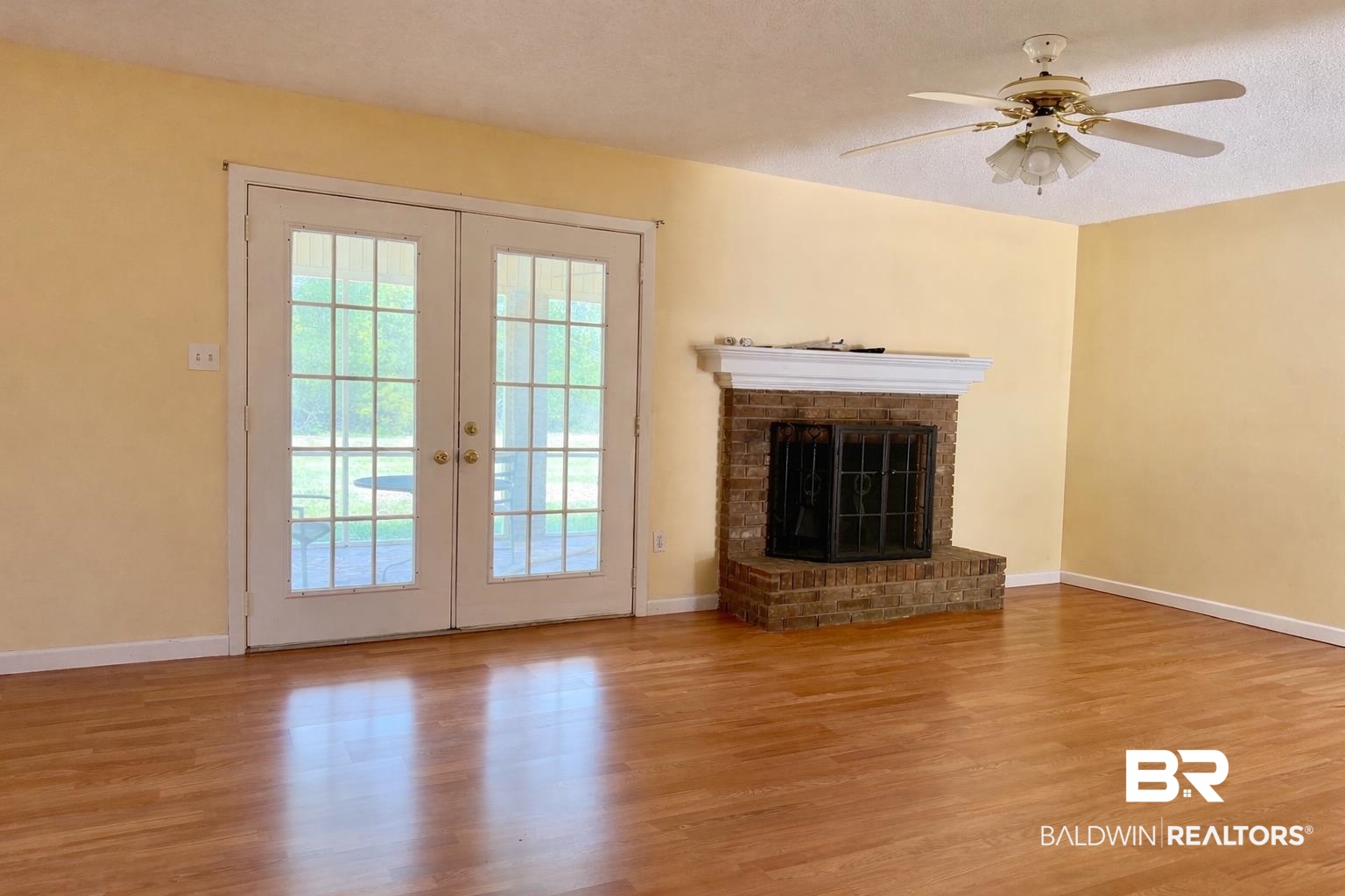 294 Wolf Log Road Flomaton, AL 36441 - Photo 3 of 14 Unfurnished living room featuring french doors, wood finished floors, a fireplace, and ceiling fan