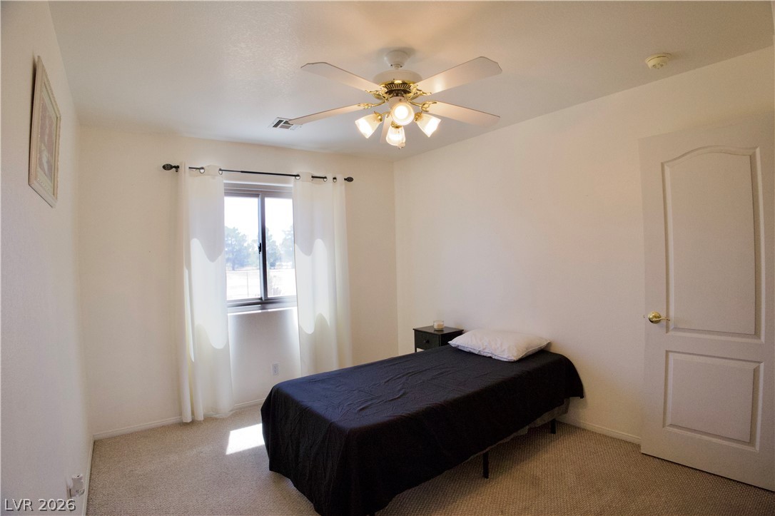1220 East Gamebird Road Pahrump, NV 89048 - Photo 18 of 50 Bedroom 2 with a functional ceiling fan and carpet flooring..