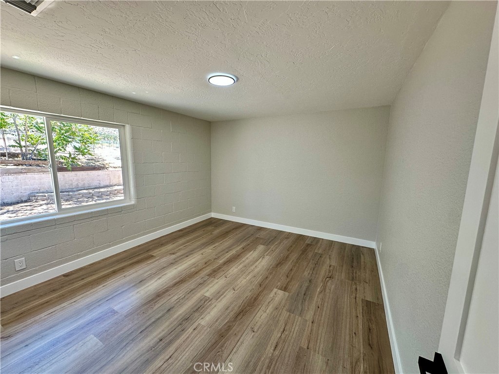 625 Tamarack Road Pinon Hills, CA 92372 - Photo 11 of 27 an empty room with wooden floor and windows