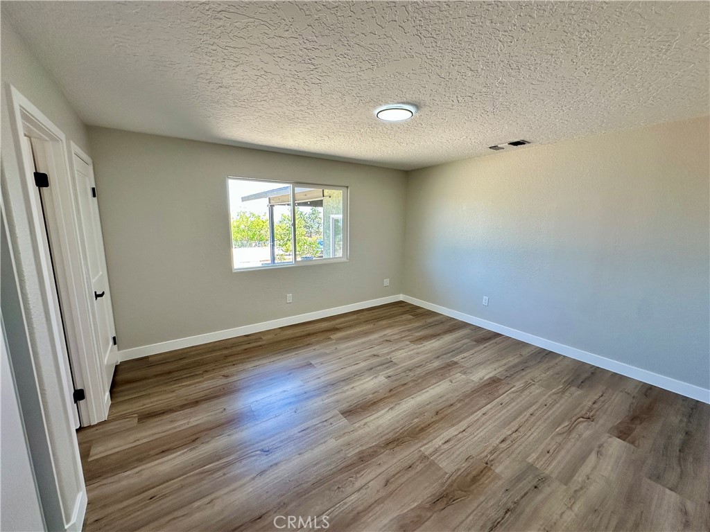 625 Tamarack Road Pinon Hills, CA 92372 - Photo 14 of 27 an empty room with wooden floor and window