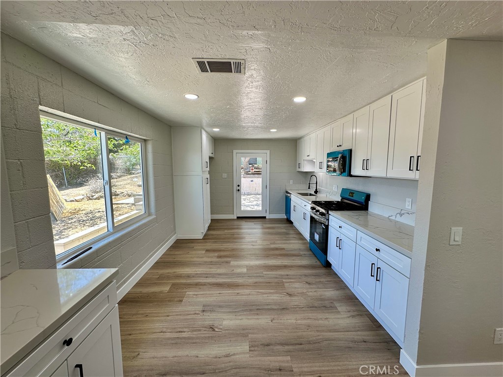 625 Tamarack Road Pinon Hills, CA 92372 - Photo 3 of 27 a large kitchen with kitchen island granite countertop a large counter top stainless steel appliances a sink cabinets and a window