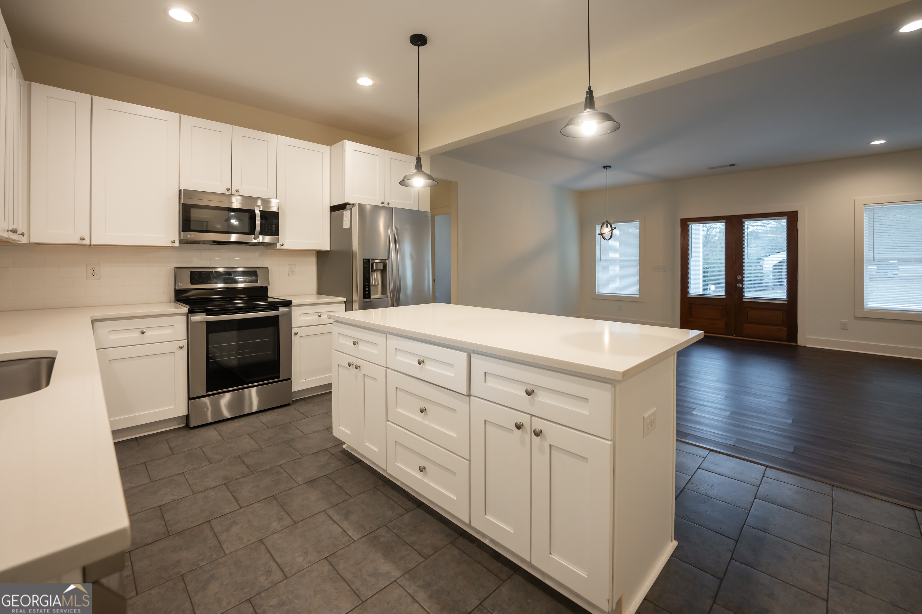 1020 Bell Circle Madison, GA 30650 - Photo 6 of 17 a kitchen with kitchen island white cabinets stainless steel appliances and wooden floor