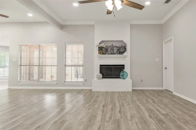 an empty room with wooden floor ceiling fan and windows