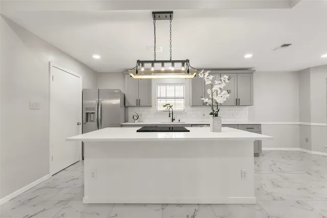 a view of a kitchen with kitchen island a sink stainless steel appliances and cabinets
