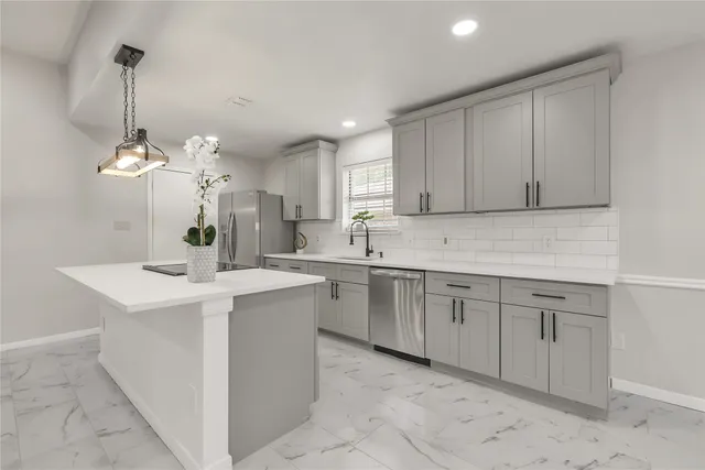 a kitchen with a sink and dishwasher with white cabinets