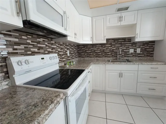 a kitchen with white cabinets granite counter tops and a stove