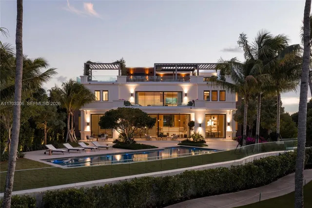 a view of a building with floor to ceiling windows and a yard with palm trees