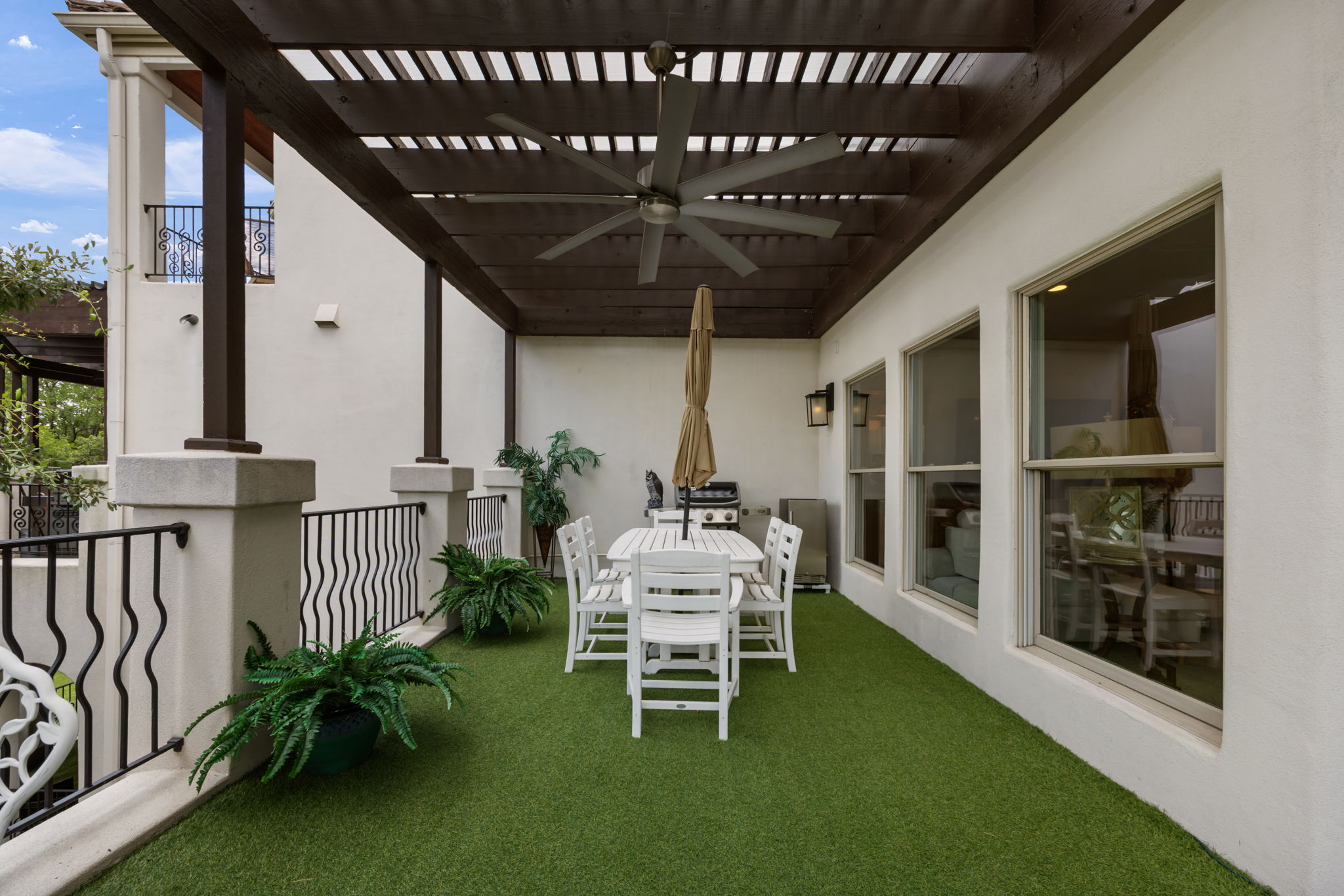 1910 Rue De St Tropez, Unit 6 Austin, TX 78746 - Photo 14 of 37 An inviting covered patio featuring a slatted pergola and turf flooring for comfortable outdoor gatherings.