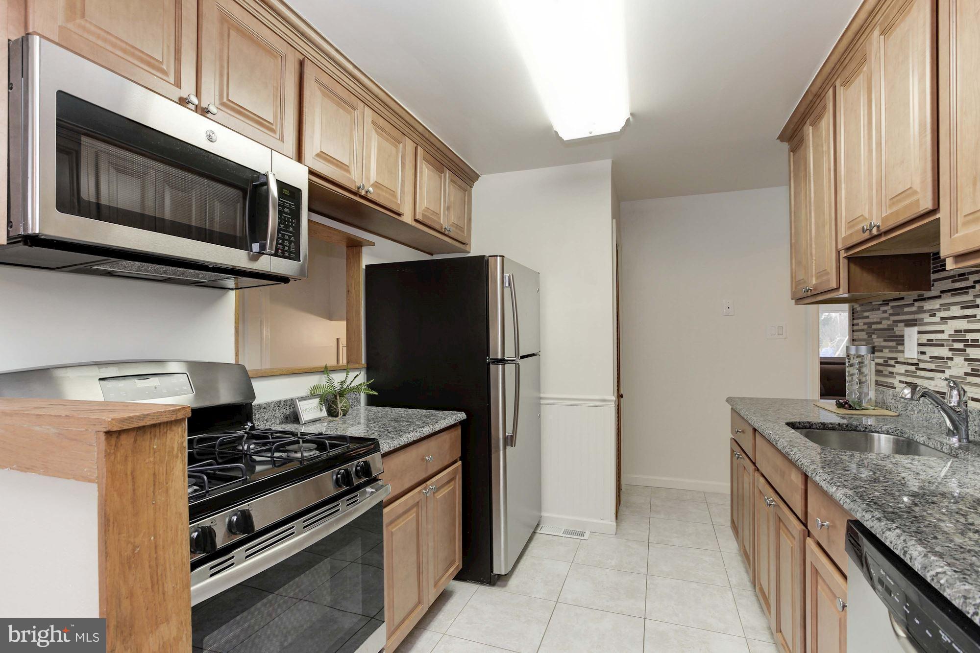 11704 Joseph Mill Road Silver Spring, MD 20906 - Photo 8 of 20 a kitchen with stainless steel appliances granite countertop a stove microwave and refrigerator