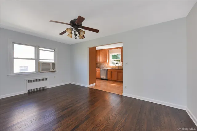 a view of an empty room with window and wooden floor