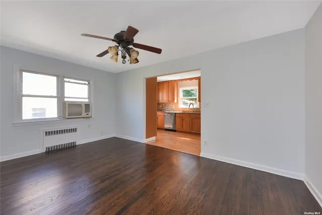 a view of an empty room with window and wooden floor