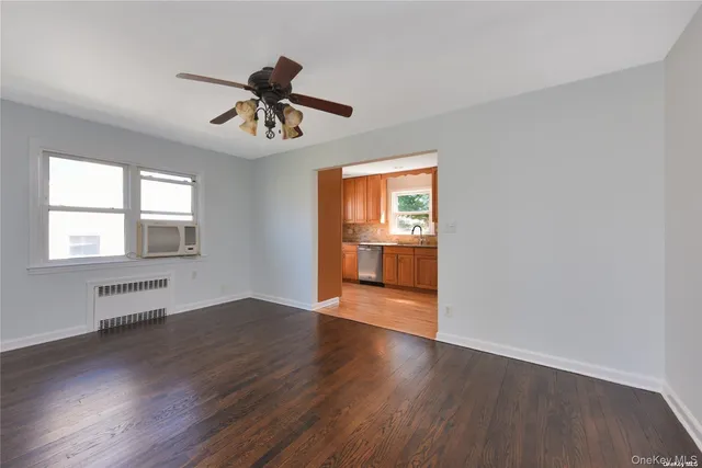 a view of an empty room with window and wooden floor