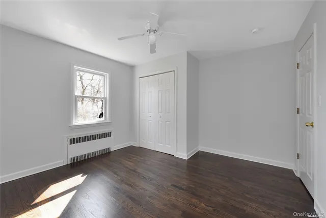 an empty room with wooden floor cabinet and windows