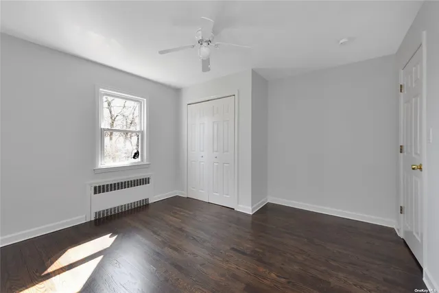 an empty room with wooden floor cabinet and windows