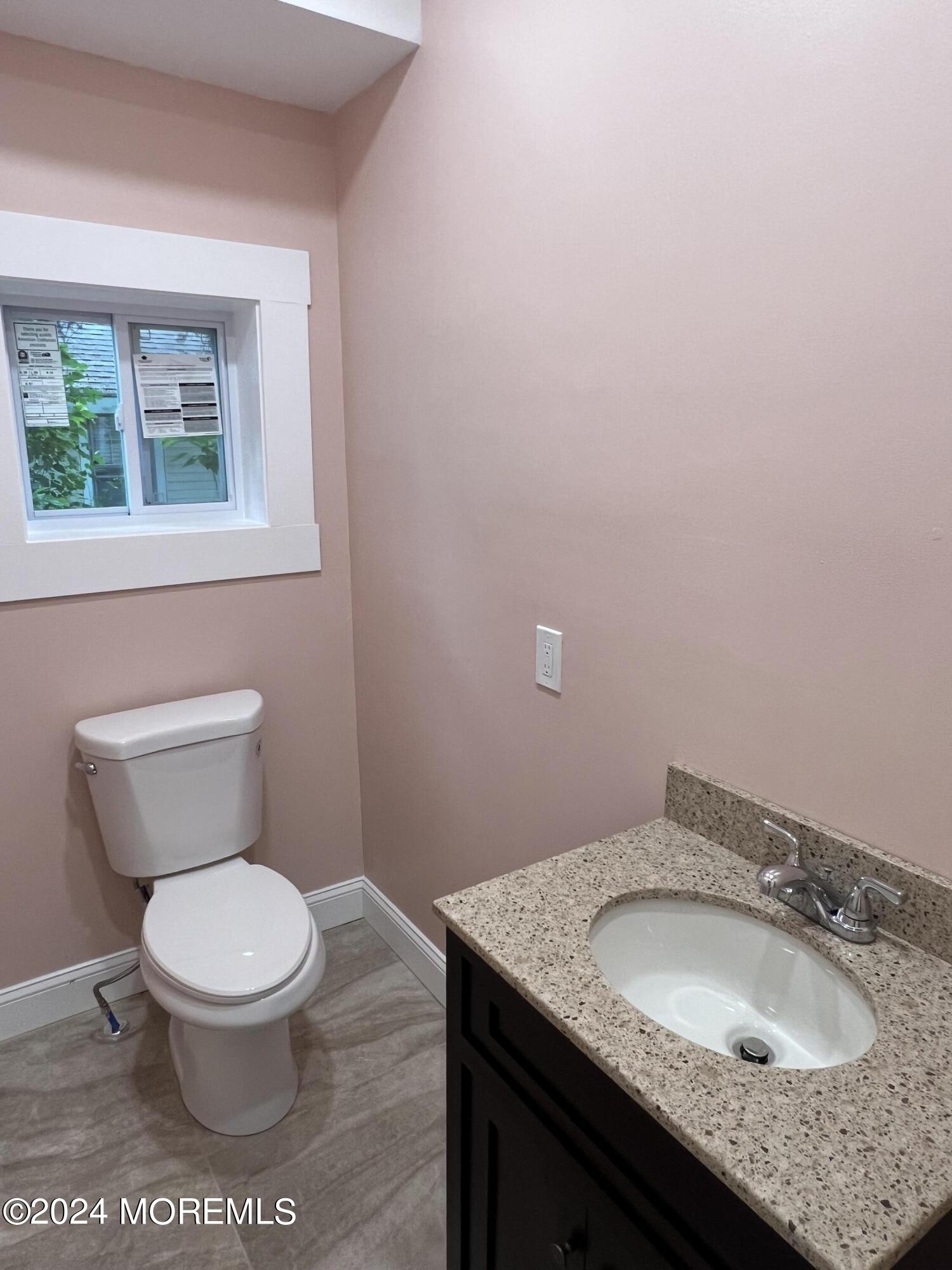 815 Clark Street, Unit 1 Point Pleasant, NJ 08742 - Photo 9 of 10 a bathroom with a granite countertop toilet a sink and mirror