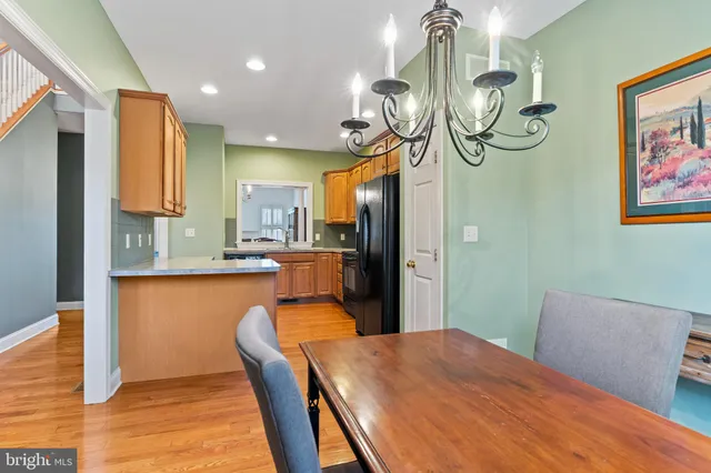 a kitchen with stainless steel appliances granite countertop a table chairs in it and wooden floors