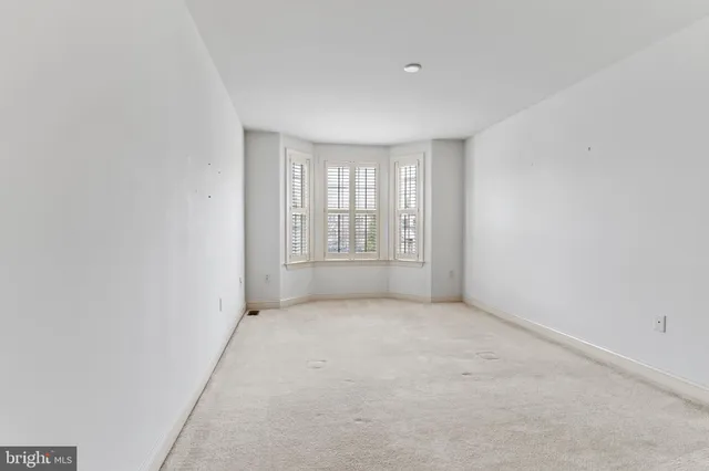 an empty room with windows and bed