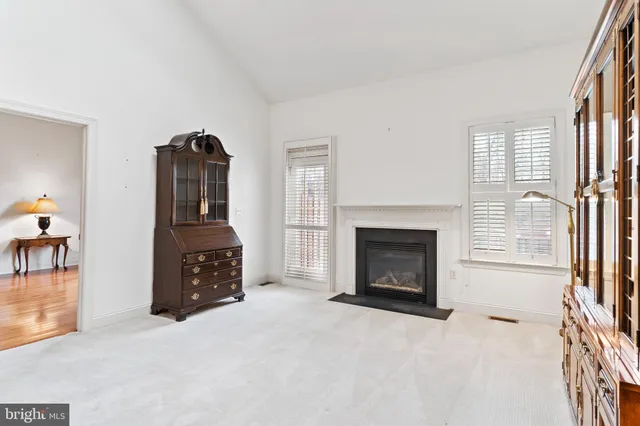 an empty room with windows fireplace and fans