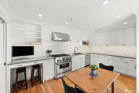 a kitchen with a stove a sink cabinets and wooden floor