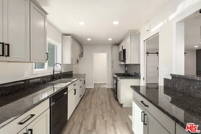 a large kitchen with stainless steel appliances granite countertop a lot of counter space and wooden floor