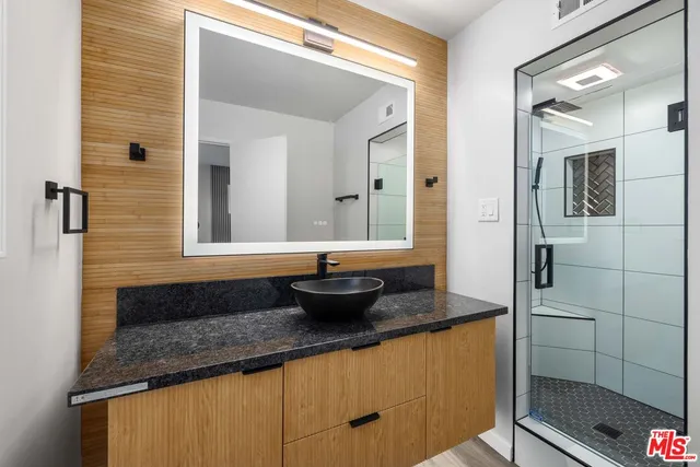 a bathroom with a granite countertop sink a large mirror and shower