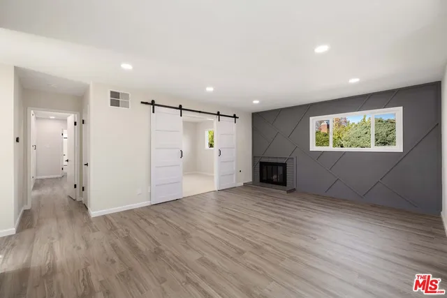 an empty room with wooden floor fireplace and windows