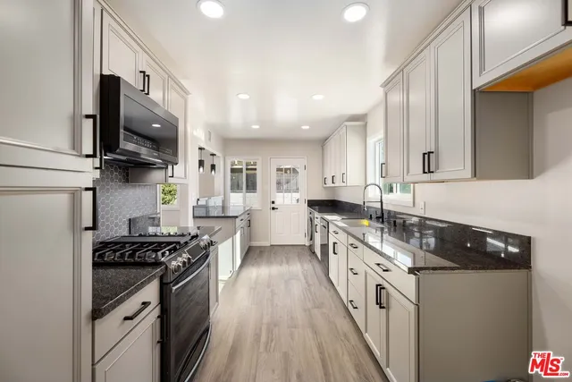 a kitchen with stainless steel appliances granite countertop a stove a sink and a microwave