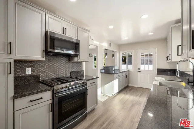 a large kitchen with stainless steel appliances granite countertop a stove a sink and a microwave