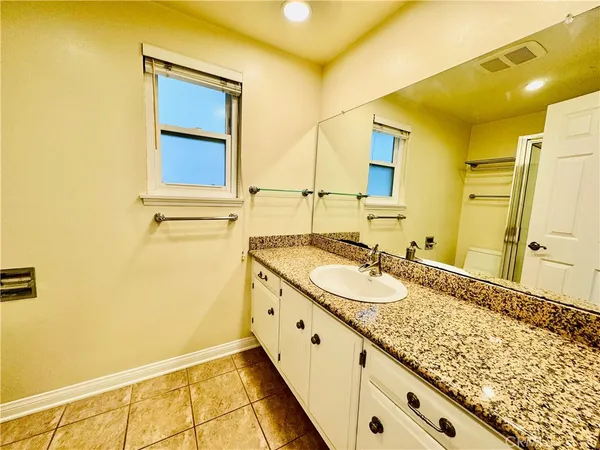 a bathroom with a granite countertop sink and a mirror