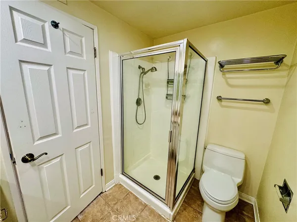 a bathroom with a granite countertop a glass door shower a toilet and a sink