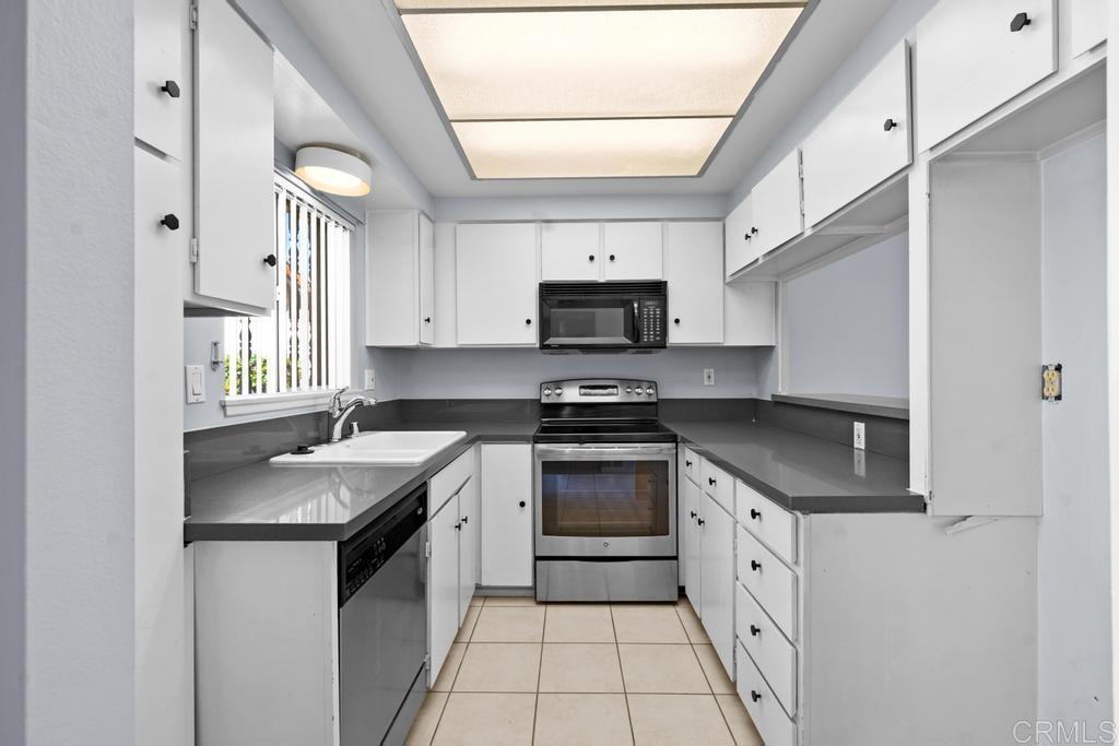 12228 Rancho Bernardo Road, Unit B San Diego, CA 92128 - Photo 3 of 35 a kitchen with granite countertop a sink stove a refrigerator and a microwave