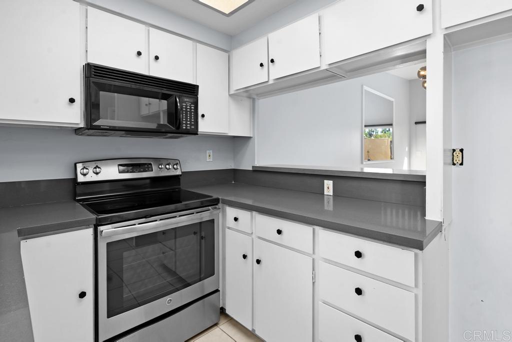12228 Rancho Bernardo Road, Unit B San Diego, CA 92128 - Photo 5 of 35 a kitchen with granite countertop white cabinets stainless steel appliances and sink