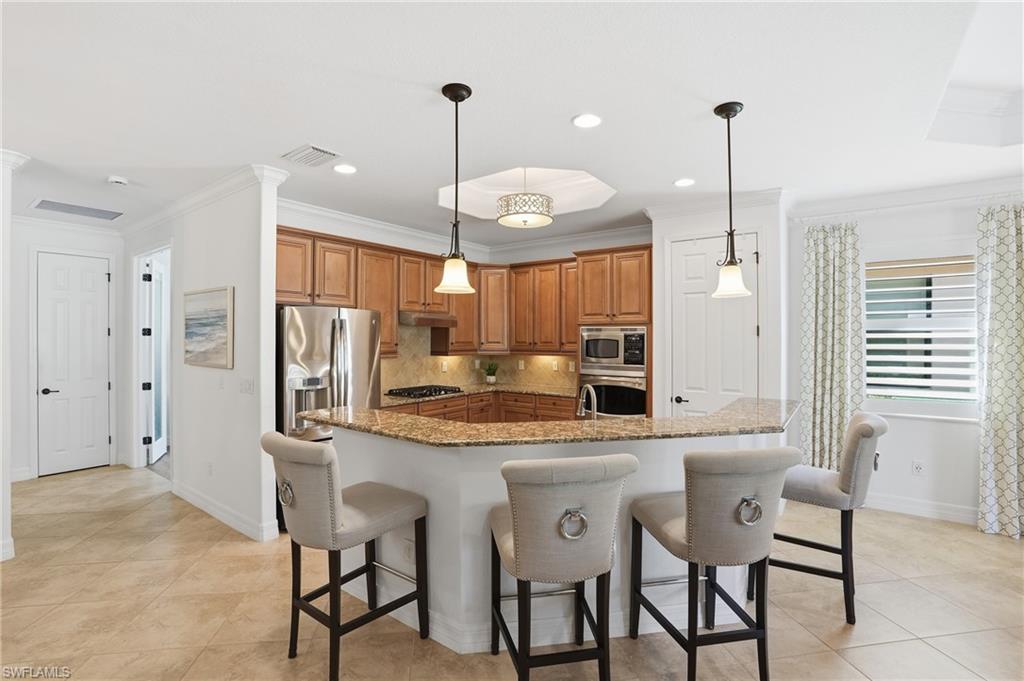 3022 Aviamar Circle Naples, FL 34114 - Photo 14 of 49 a kitchen with stainless steel appliances kitchen island granite countertop a table chairs in it and wooden floors