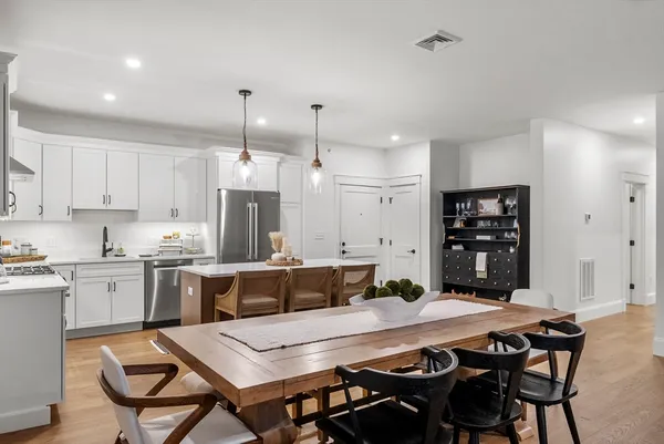a kitchen with stainless steel appliances kitchen island a table and chairs in it