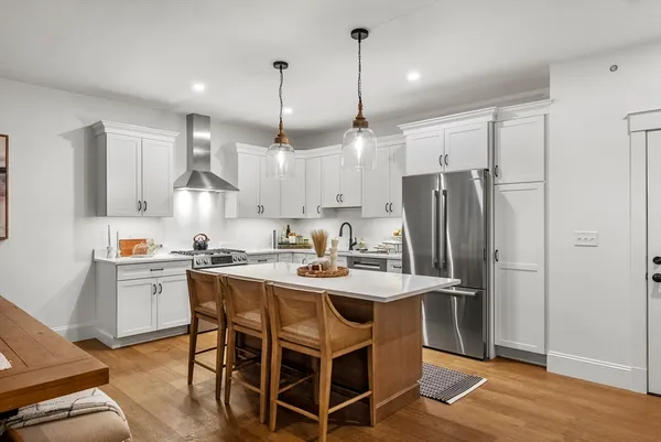 a kitchen with stainless steel appliances granite countertop a sink a stove a refrigerator and island with wooden floor