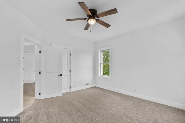 an empty room with fan and windows