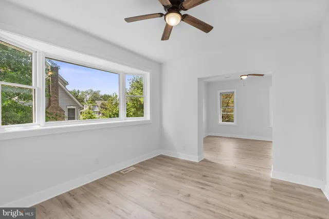 a view of an empty room with a window and wooden floor