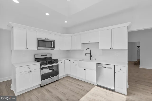 a kitchen with white cabinets sink and stainless steel appliances