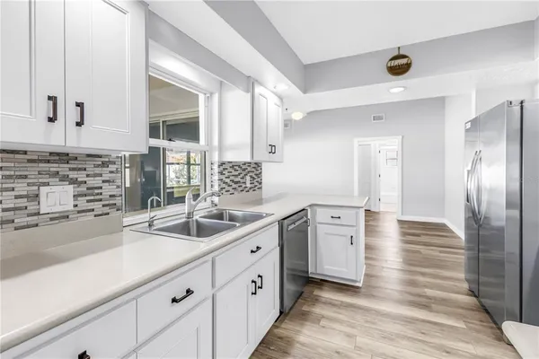 a kitchen with cabinets stainless steel appliances and wooden floor